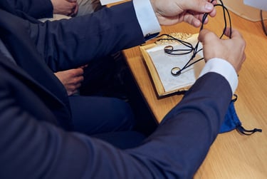 The best man placing wedding bands on necklaces on a plate prior to wedding ceremony.