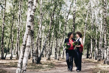 Two brides walking in a birch forest.