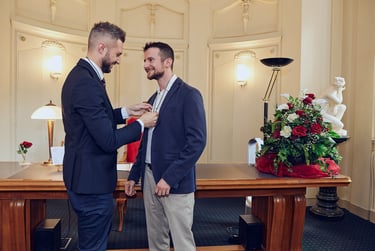Der Bräutigam legt eine Hochzeitskette mit einem Band um den Hals seines Mannes.