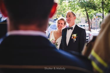 Braut und Bräutigam hören sich draußen eine Rede an.