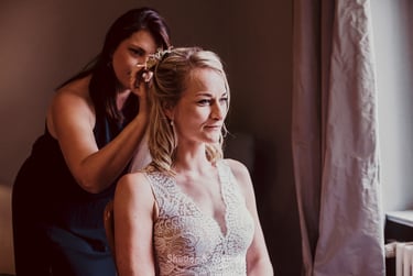 Trauzeugin, die die Haare der Braut richtet.