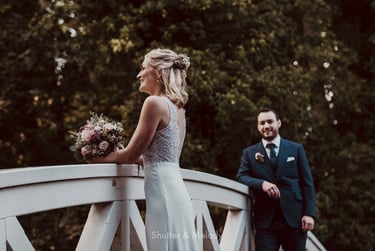 Groom looking at bride on a wooden bridge.