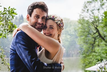 Bride and groom hugging while it's raining. 