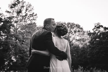 Groom kissing bride on the side of her head.