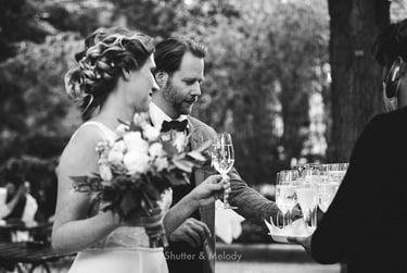 Bride and groom picking up glasses of champagne from a tray.