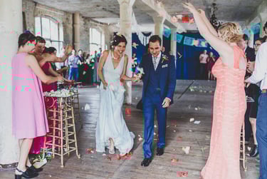 Bride and groom leaving the ceremony having flower petals thrown at them.