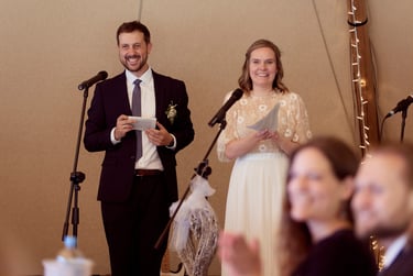 Bride and groom holding speeches and smiling.