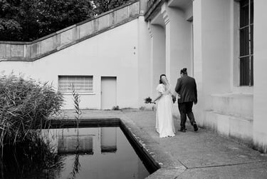 Newlyweds walking along a pond in a park.