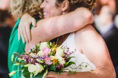Bride holding flowers and hugging a guest.