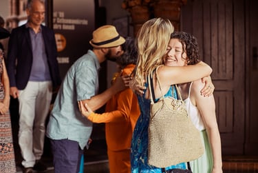 Smiling bride hugging guests in church entryway.