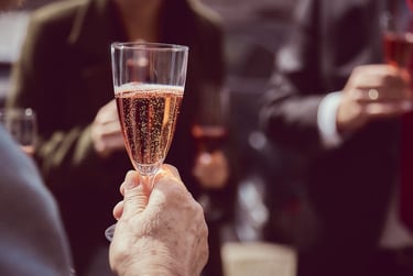 Hand holding a glass of sparkling rose wine.