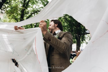 Groom cutting out a heart in bed sheets.