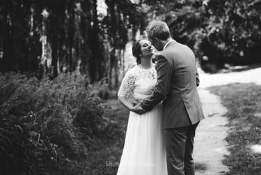 Braut und Bräutigam stehen auf einem Weg und sind dabei, sich zu küssen.