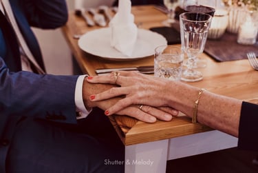 Weibliche Hand auf einer männlichen Hand auf einem Tisch.