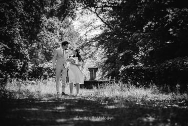 Bride and groom walking in a park with their infant.