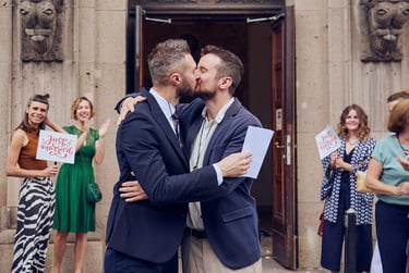 Newylwed gay couple kissing in front of wedding guests.