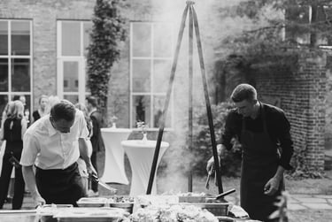 Two cooks grilling food at a wedding reception.