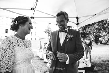 Groom and bride laughing during a civil ceremony under a canopy.