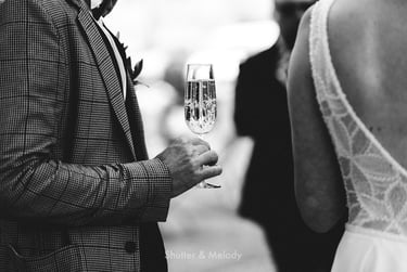 Nahaufnahme des Bräutigams, der ein Glas Champagner hält.