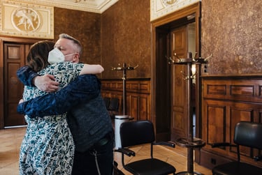 Groom wearing a mask hugging a guest.