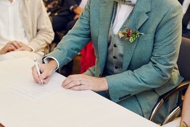 Groom in a green suit signing wedding certificate.