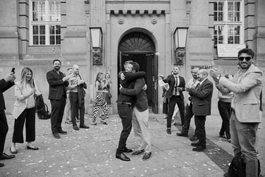 Two grooms hugging each other outside of the civil registry building.