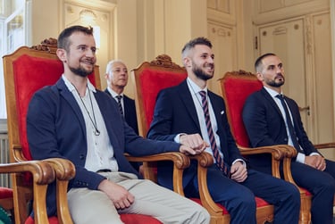 Grooms sitting on red chair during a civil wedding ceremony.