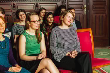 Wedding guests sitting on red chairs during wedding ceremony.