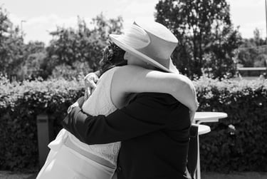 Wedding guest wearing a hat hugging the bride.