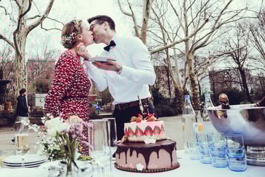 Groom kissing bride while eating cake.