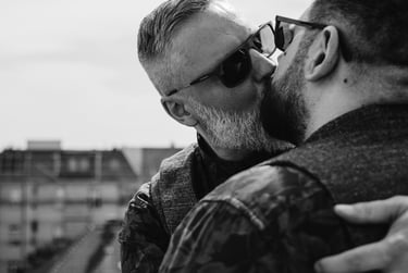 Grooms kissing on a balcony.