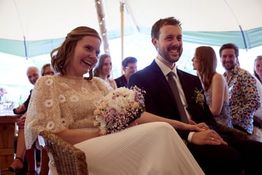 Married couple laughing at the speeches in a tent.