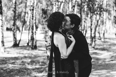 Two brides kissing each other in a birch forest.