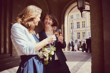 Ein lesbisches Paar stößt mit einem Glas Sekt an.
