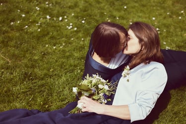 An LGBTQ couple kissing on the grass.