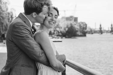 Groom hugging bride from behind and kissing her on the cheek.