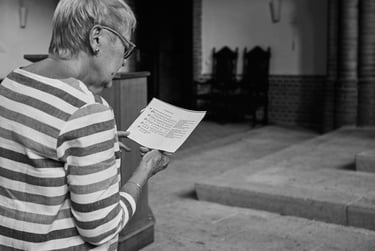 An older wedding guest singing from a songbook at church.
