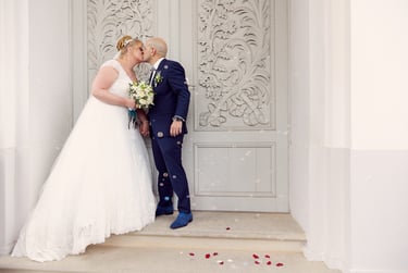 Bride and groom kissing in front of a carved door.