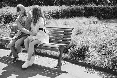 A young couple sitting on a bench in a park.