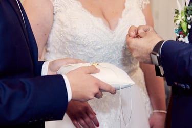 Der Bräutigam hält einen Ring und steckt ihn der Braut an den Finger.