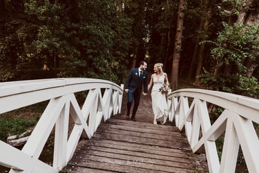 Bride and groom walking over a bridge looking at each other.