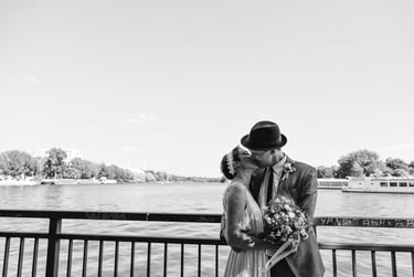 Bride and groom kissing by the river on a sunny day.