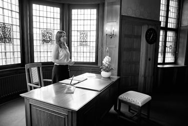 Standesbeamter, der hinter einem Schreibtisch steht.