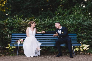 Braut und Bräutigam sitzen auf einer blauen Bank.