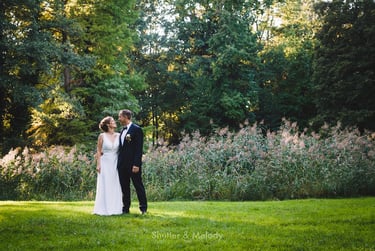 Braut und Bräutigam stehen auf einer Wiese.