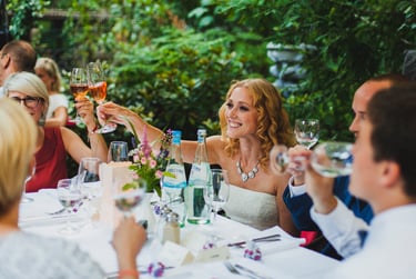 Bride toasting wedding guests at a table.