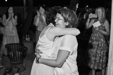 Two newlywed wives hugging each other at the wedding reception.