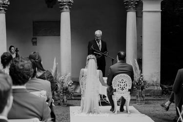 Bride and groom sitting in metal chairs during a wedding ceremony.