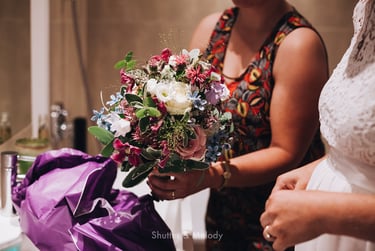 Maid of honor handing over the bridal bouquet to the bride.