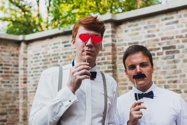 Two male wedding guests with photo booth accessories.